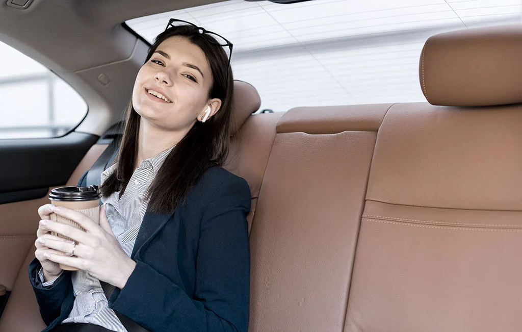 Businesswoman enjoying coffee while on airport car service ride